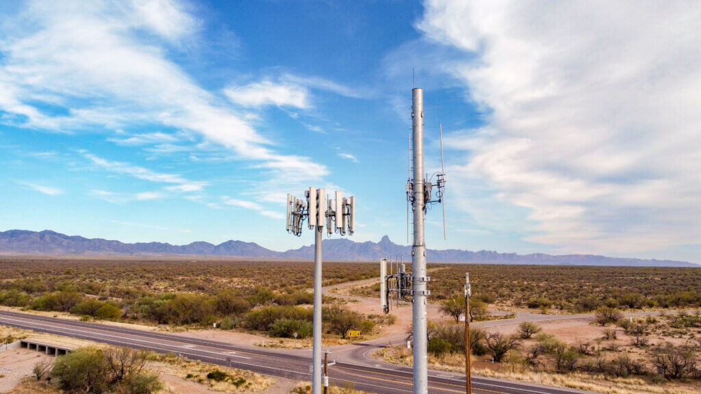 2 cellphone towers providing service for cellular phone plans, there is a sprawling desert behind them
