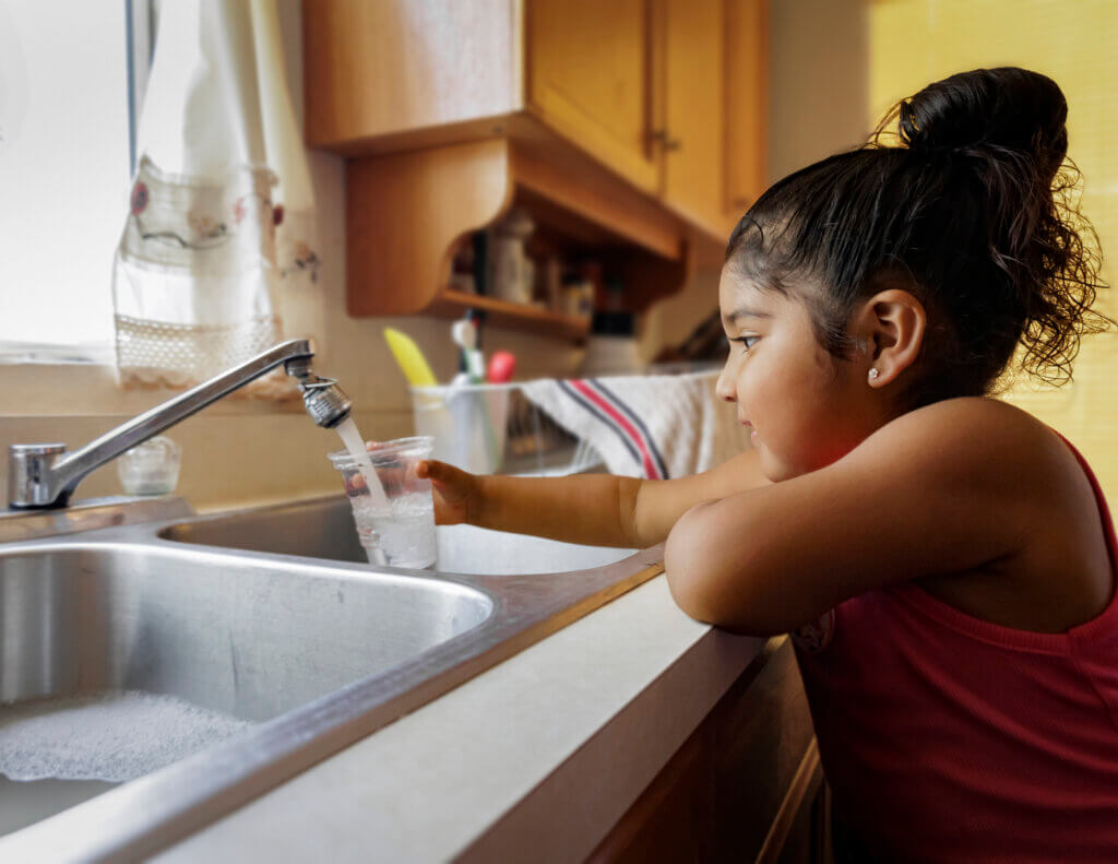Water services provided by Tohono O'odham Utility Authority as a young girl fills a cup with water from the kitchen sink